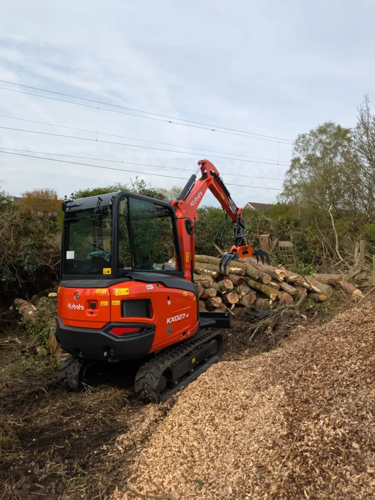 Digger stacking willow timber beside a pile of woodchip